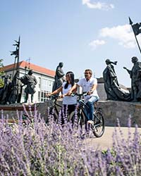 Paar fährt mit dem Rad am Nibelungenbrunnen vorbei 