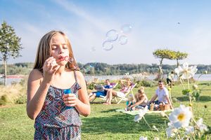Mädchen macht Seifenblasen auf Picknickwiese an der Tullner Donaulände