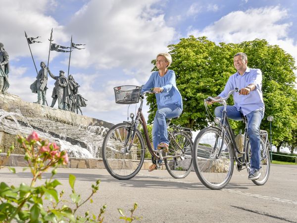 Frau und Mann am Rad beim Nibelungenbrunnen 