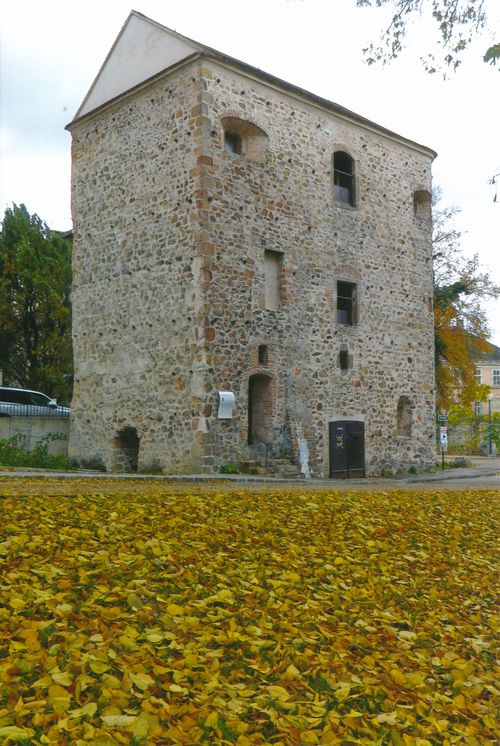 Herbstlicher Anblick des alten Römerturms mit umliegenden Herbstblättern.