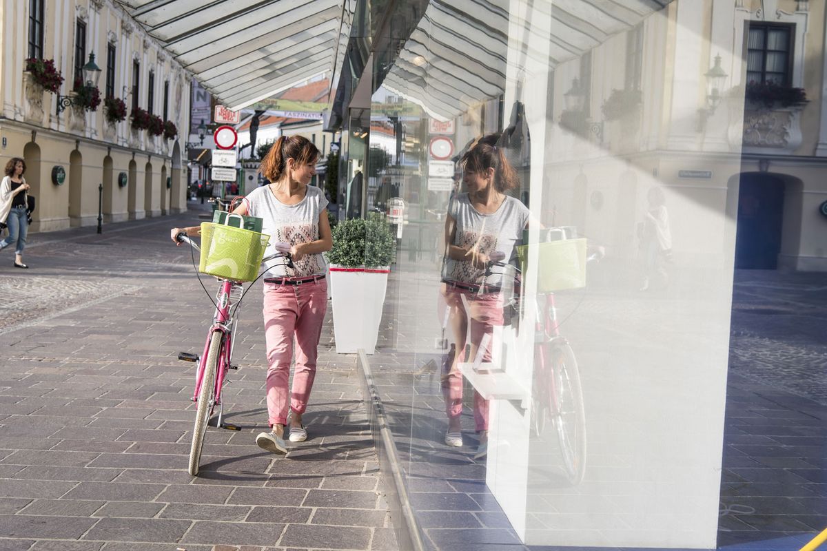 Dame mit Fahrrad blickt in eine Geschäftauslage