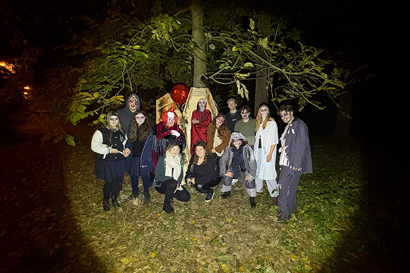 Gruppe verkleidet als Gruselgestalten vor einem Sarg im Wald